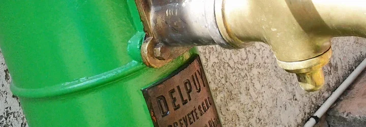 Pompe à eau ancienne peinte en vert, avec ses robinets en laiton